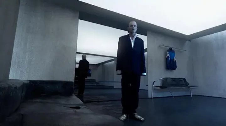 Balenciaga Afterworld Fall 2021 — an avatar standing in a grey, minimalist concrete showroom, a garment on a rail behind